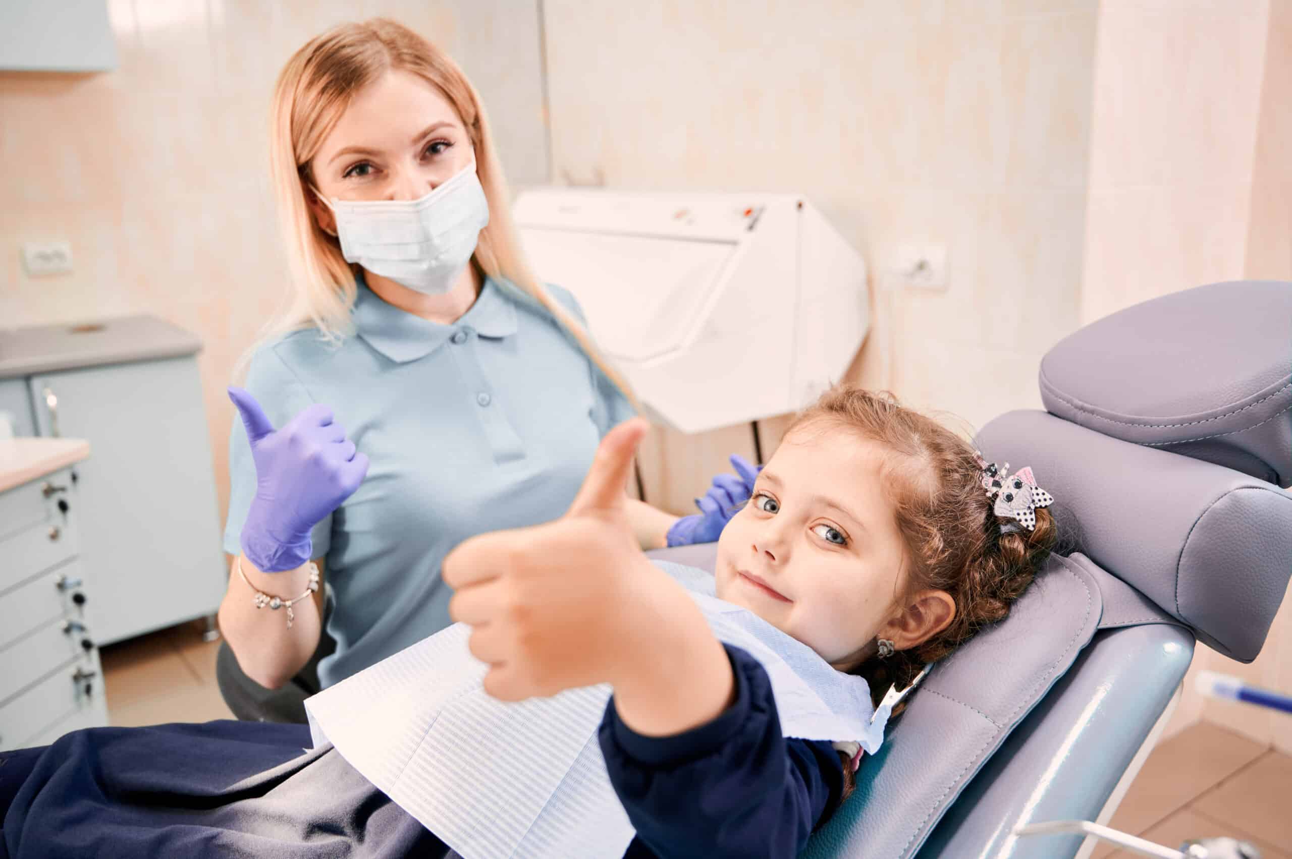 Pediatric Dentistry by a dentist on the child facing on the camera showing thumb ups for positivity