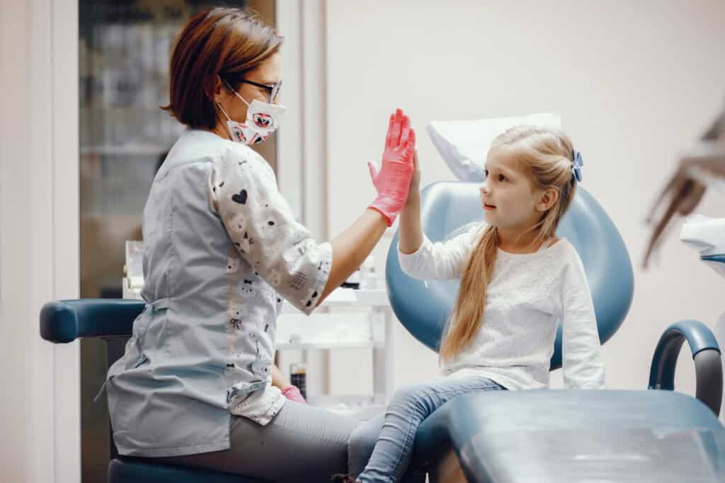 Pediatric dentist in Great Neck, NY helping a young child feel comfortable during a dental visit.