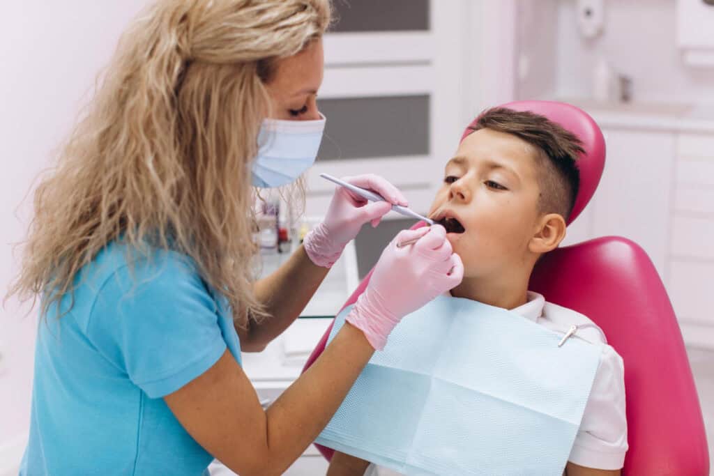 Pediatric dentist examining a child during a gentle first dental visit in a child-friendly dental office.