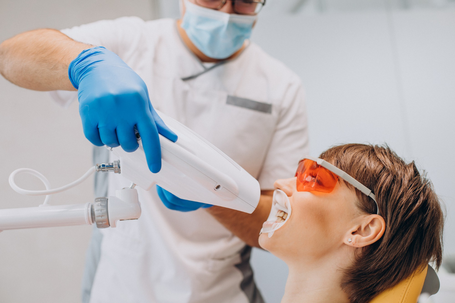 Dentist performing a professional teeth whitening treatment on a patient in a dental clinic.