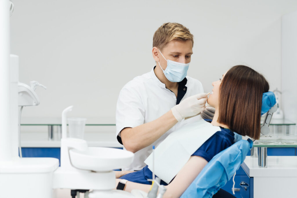 Dentist examining patient during a cosmetic dentistry consultation in a modern dental clinic.
